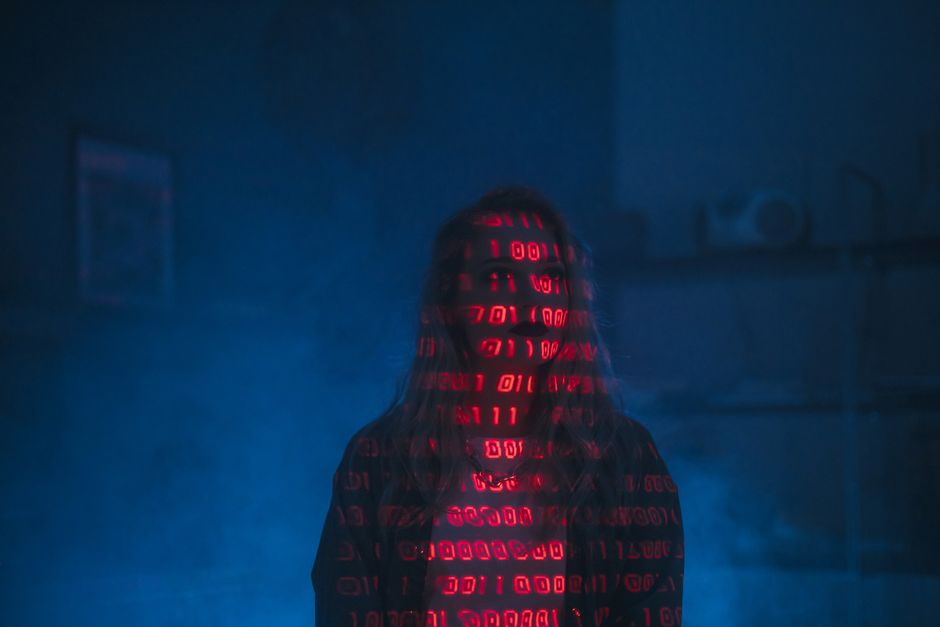 A close-up view of a modern laptop displaying a dark-themed code editor with colorful syntax highlighting, set against a dimly lit background. The laptop's keyboard is visible in the foreground, and t